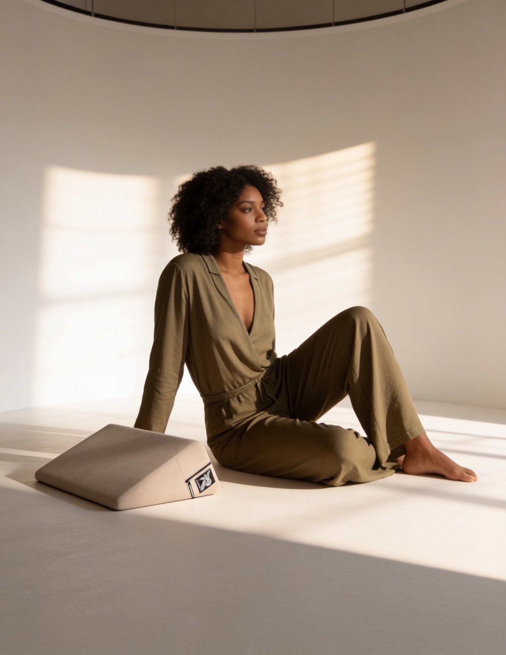 Woman in cream loungewear relaxing with Liberator positioning shapes