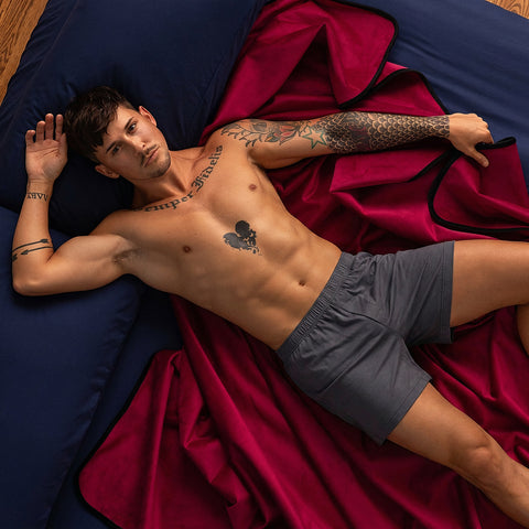 Man in charcoal sleep shorts on the merlot Fascinator throw