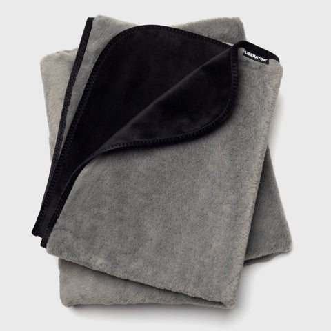 Folded gray blanket with black interior on a light gray background
