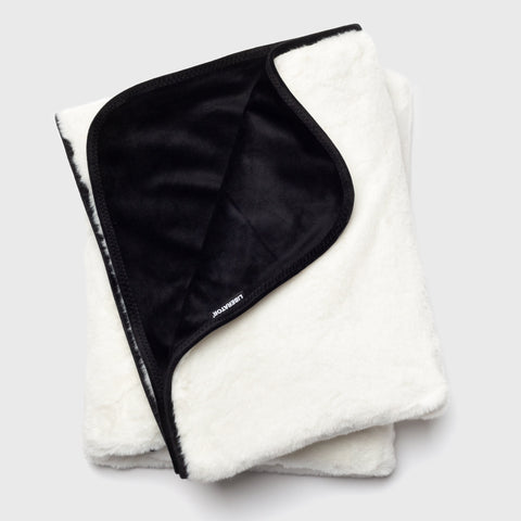 Folded white blanket with black interior on a light gray background