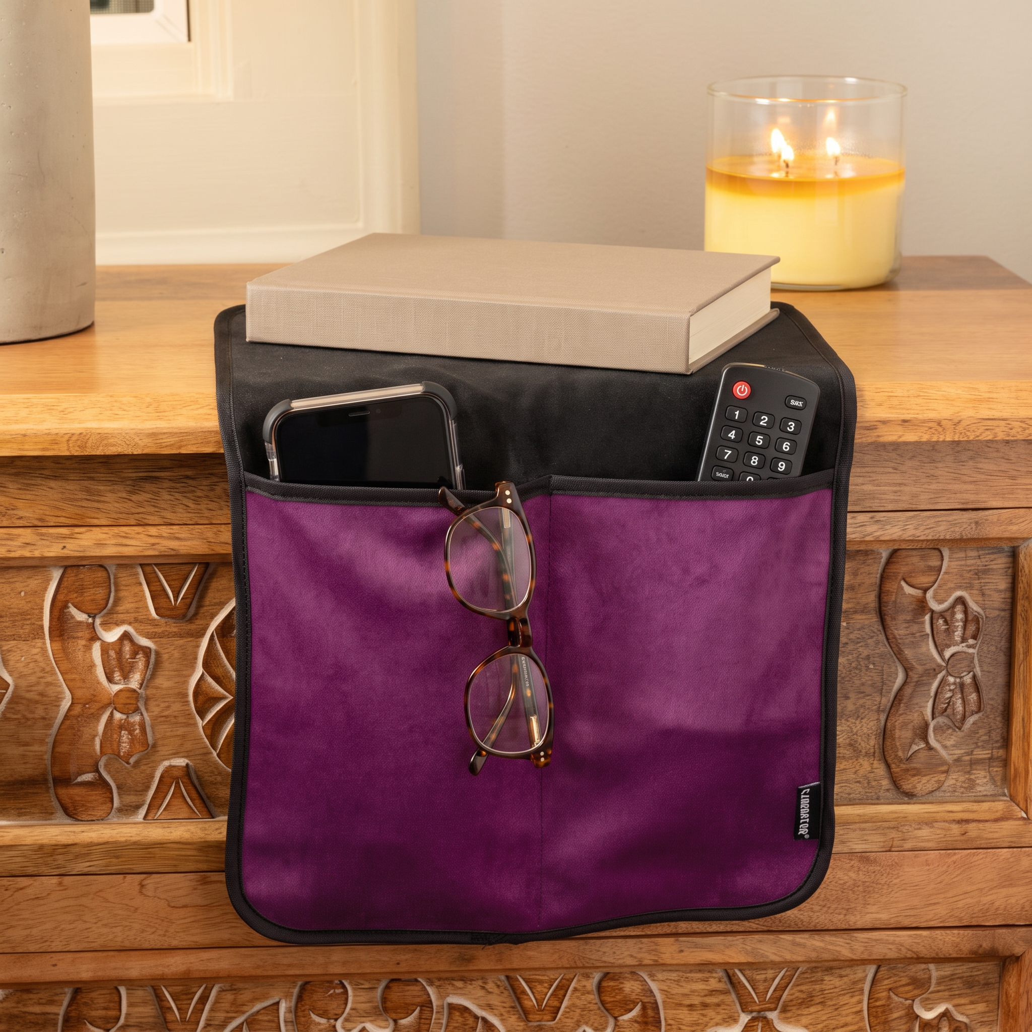 Fascinator Bedside Caddy in purple on a nightstand, holding a phone, reading glasses and remote