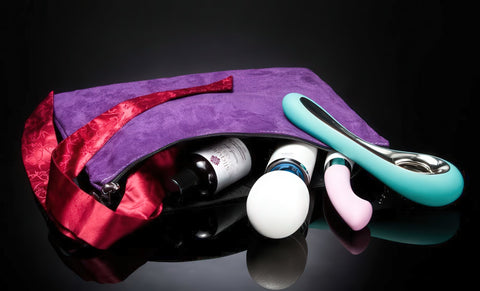 Purple toy bag with red interior containing sexual products on a black background