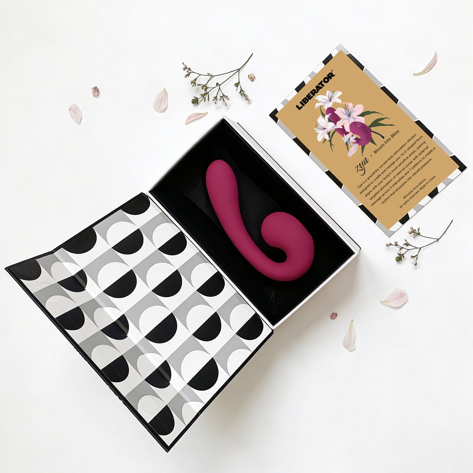 Pink curved vibrator in a decorative box with a patterned interior, on a white background.